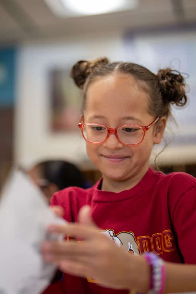 2nd grade student flips through book during lesson.